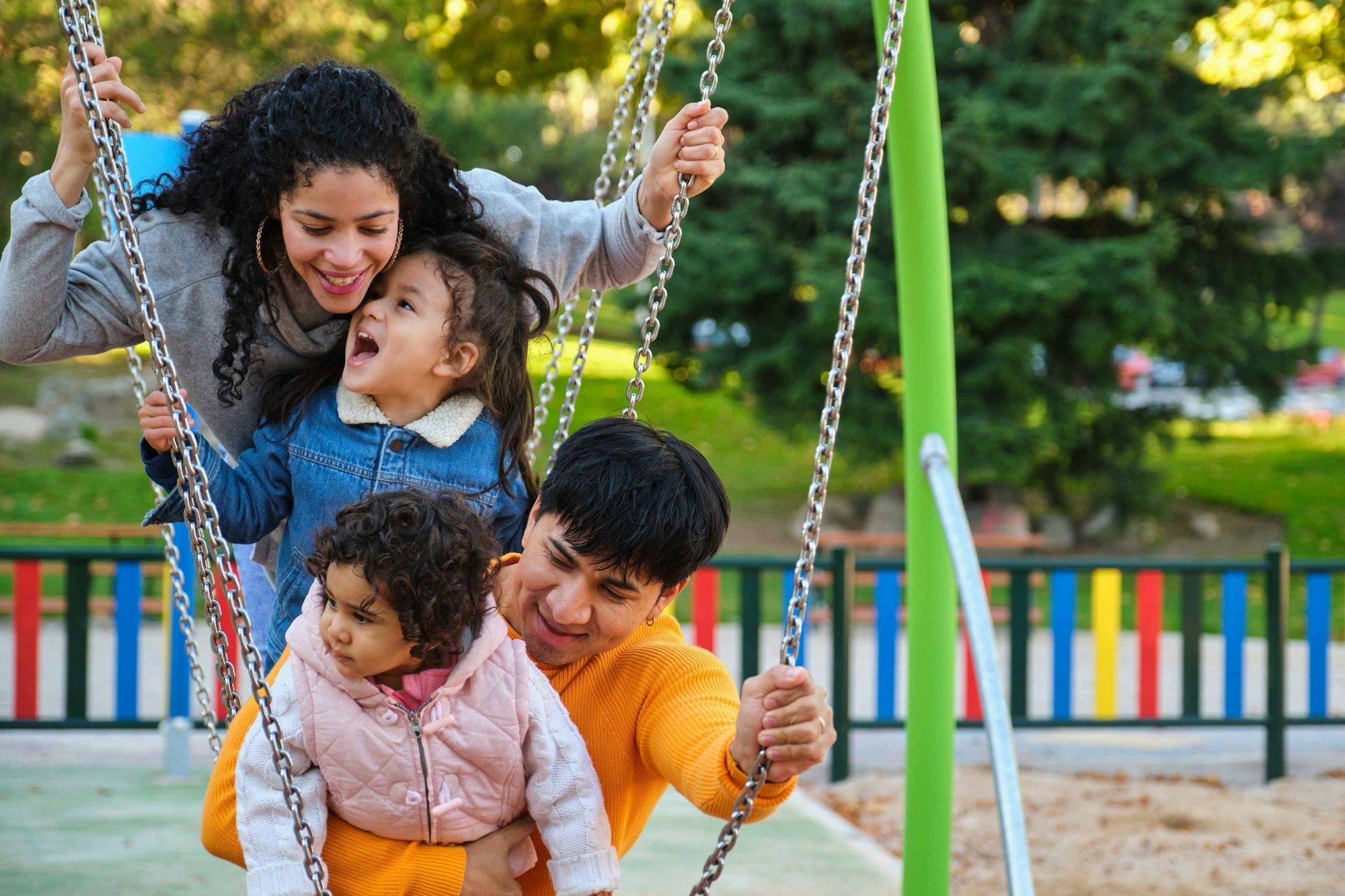 Latin family with two children playing together in a playground.